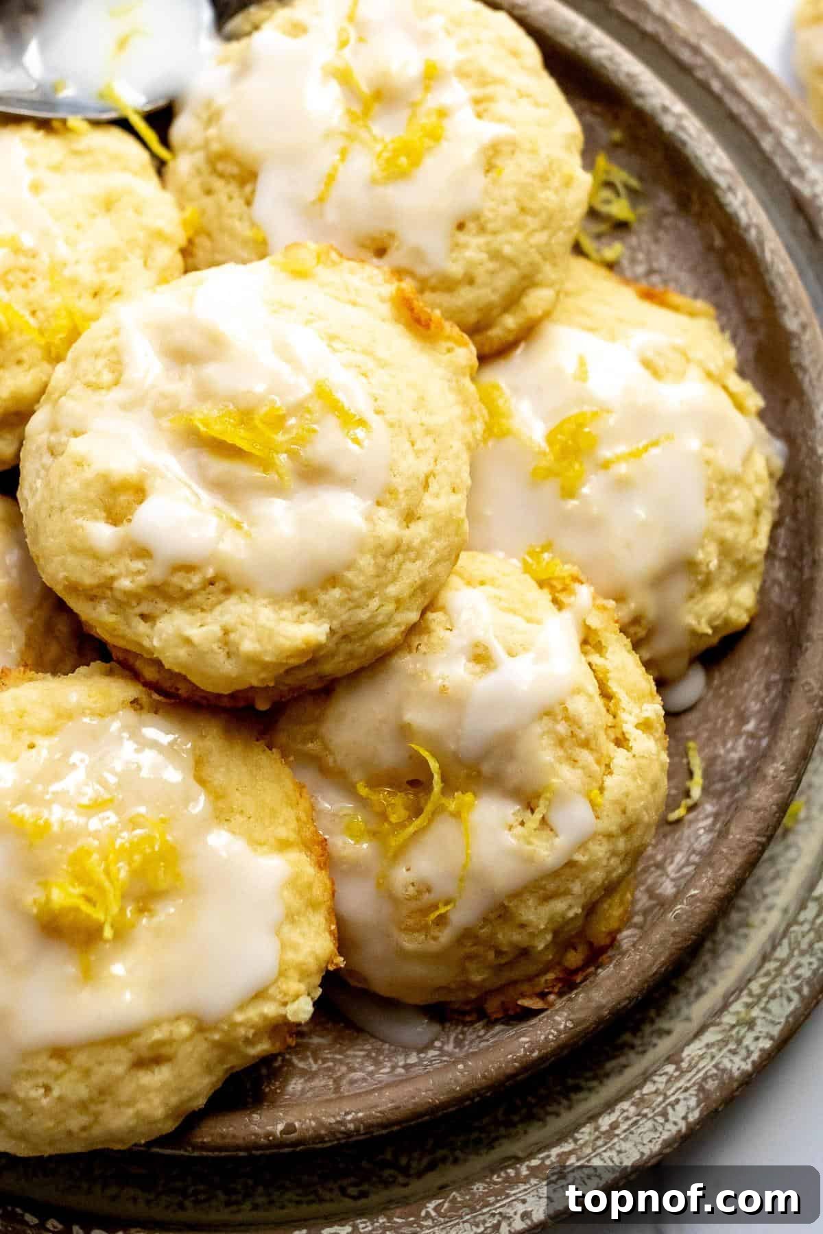 Zesty Ricotta Cloud Cookies 5 A close-up shot of freshly baked and glazed Lemon Ricotta Cookies on a beige plate, highlighting their soft texture and shiny icing.