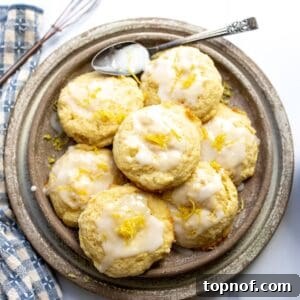 A plate full of freshly baked Lemon Ricotta Cookies with a generous drizzle of lemon icing.