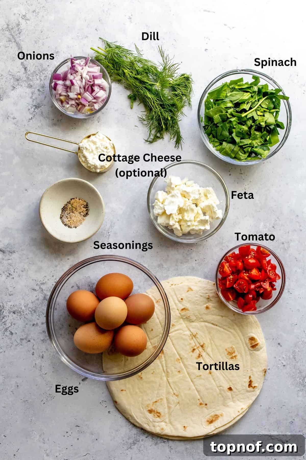 Savory Tortilla Quiche Casserole 3 An overhead image showcasing all the fresh ingredients laid out for the baked quiche recipe, including tortillas, eggs, cheese, spinach, tomatoes, and seasonings.