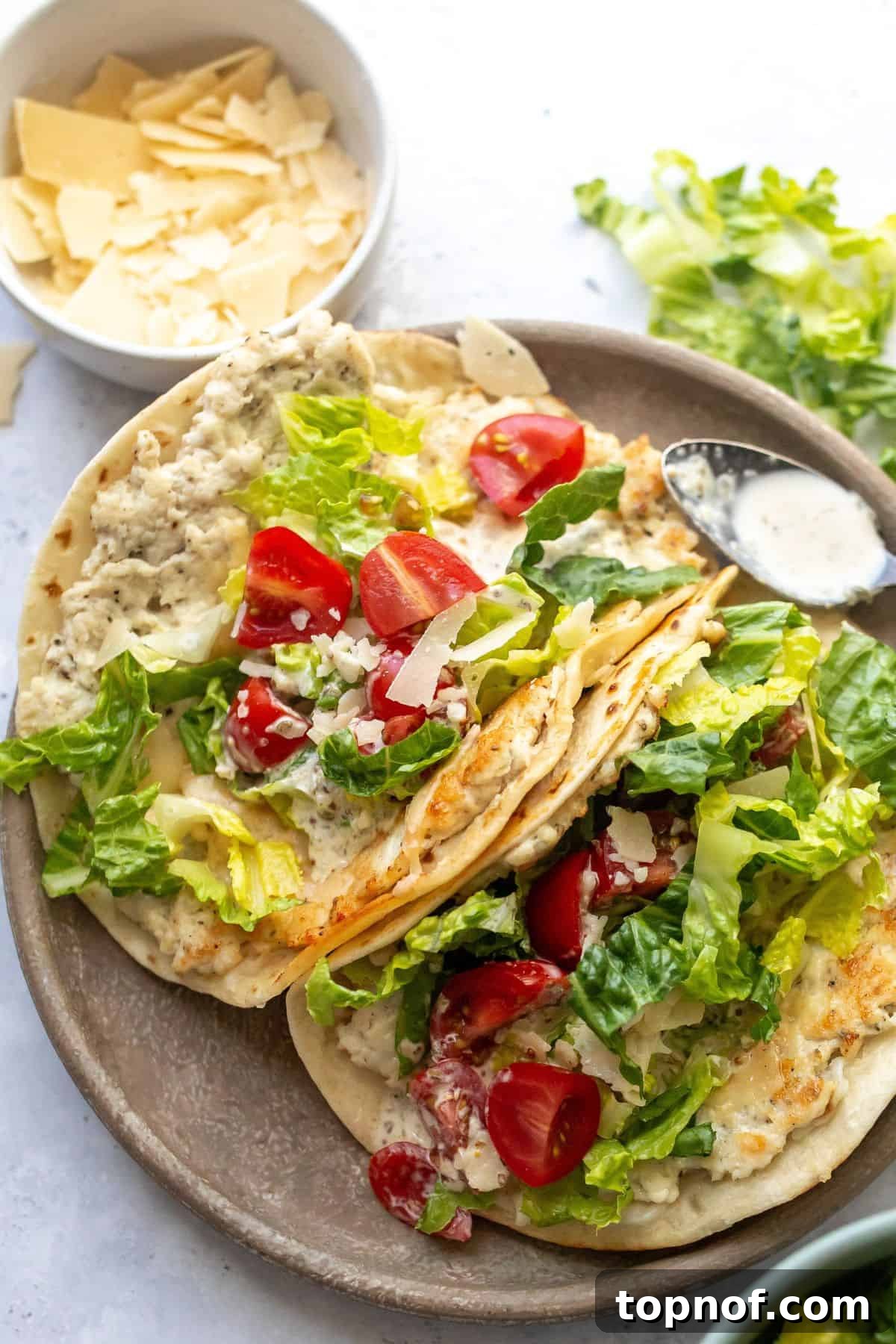 Caesar Chicken Smash Tacos 5 A stunning close-up shot of Chicken Caesar Smashed Tacos beautifully plated on a modern grey dish, accompanied by a small bowl of creamy dressing.
