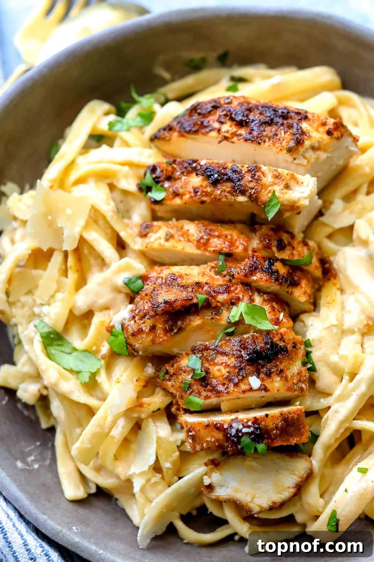 Cajun Spiced Chicken Fettuccine Alfredo 5 Up close photo of Blackened Chicken Fettuccine Alfredo in a grey bowl with sauce.