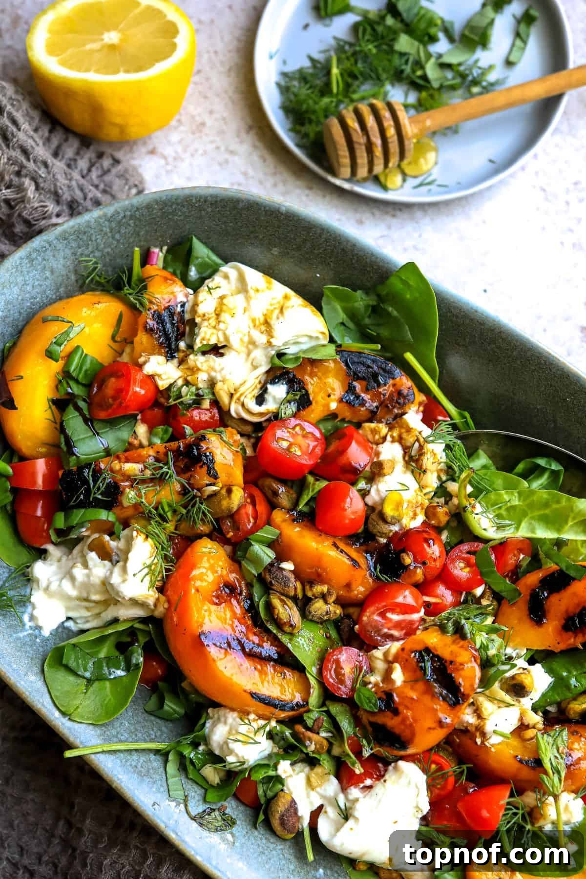 Golden Grilled Peach and Creamy Burrata Salad 6 A vibrant and colorful grilled peach burrata salad served on a blue platter.