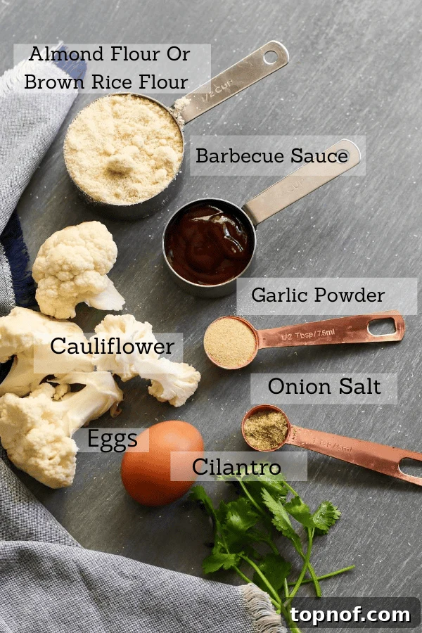 All the ingredients for this recipe laid out: fresh cauliflower, garlic powder, onion powder, eggs, BBQ sauce, almond flour
