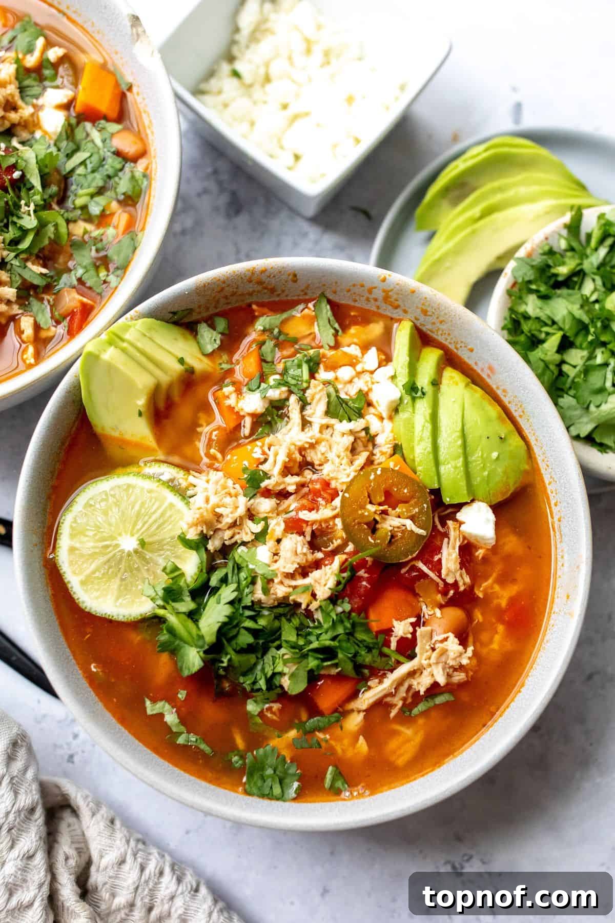 Zesty Chicken Lime Fiesta Soup 2 A ceramic bowl brimming with a fragrant Mexican Chicken Lime Soup, garnished with vibrant fresh lime wedges, ready to be enjoyed.