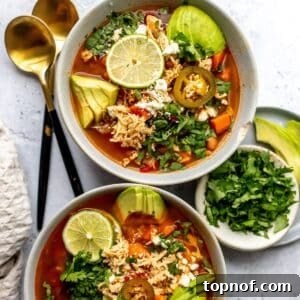 Mexican Chicken Lime Soup in two ceramic bowls with avocado and lime, visually appealing and ready to serve.
