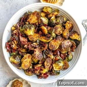 White bowl with Balsamic Honey Brussels Sprouts and honey on the side.