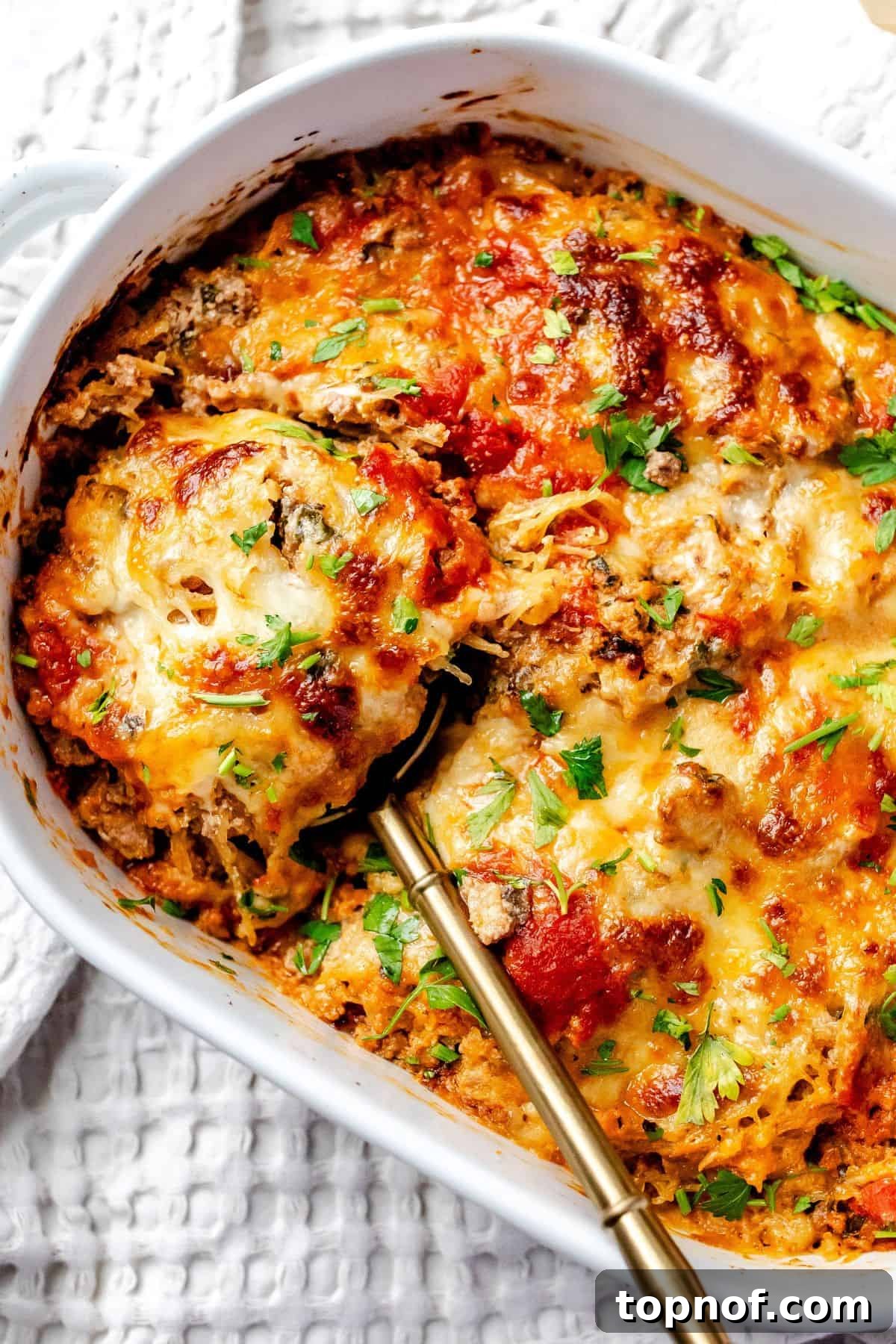 Wholesome Spaghetti Squash Lasagna 2 A white ceramic baking dish filled with golden-brown Spaghetti Squash Lasagna, with a serving spoon resting beside it, highlighting its rich, cheesy layers.