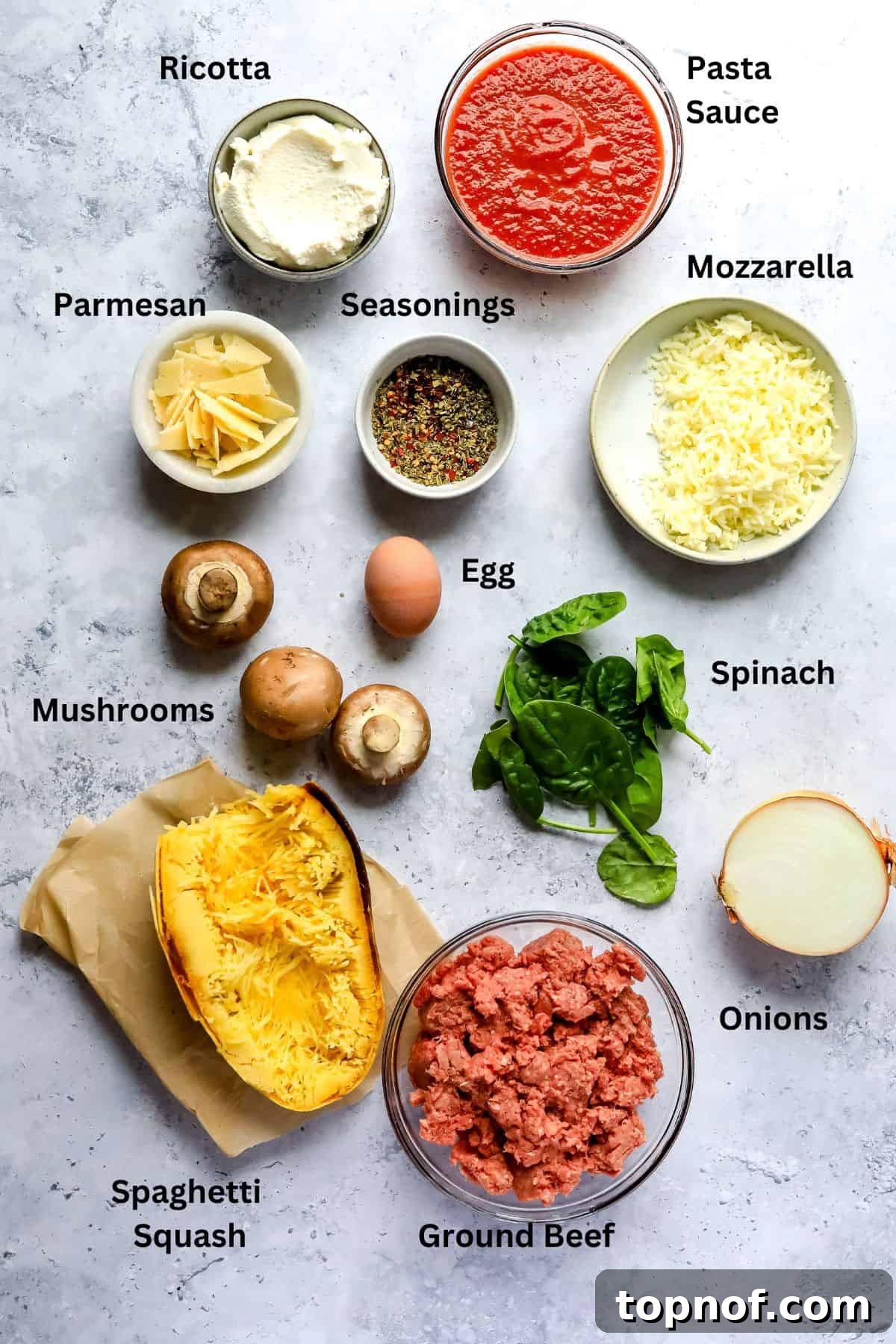 Wholesome Spaghetti Squash Lasagna 3 Various fresh ingredients for Spaghetti Squash Lasagna laid out on a kitchen counter, including bowls of cheese, sauce, ground meat, and fresh vegetables.