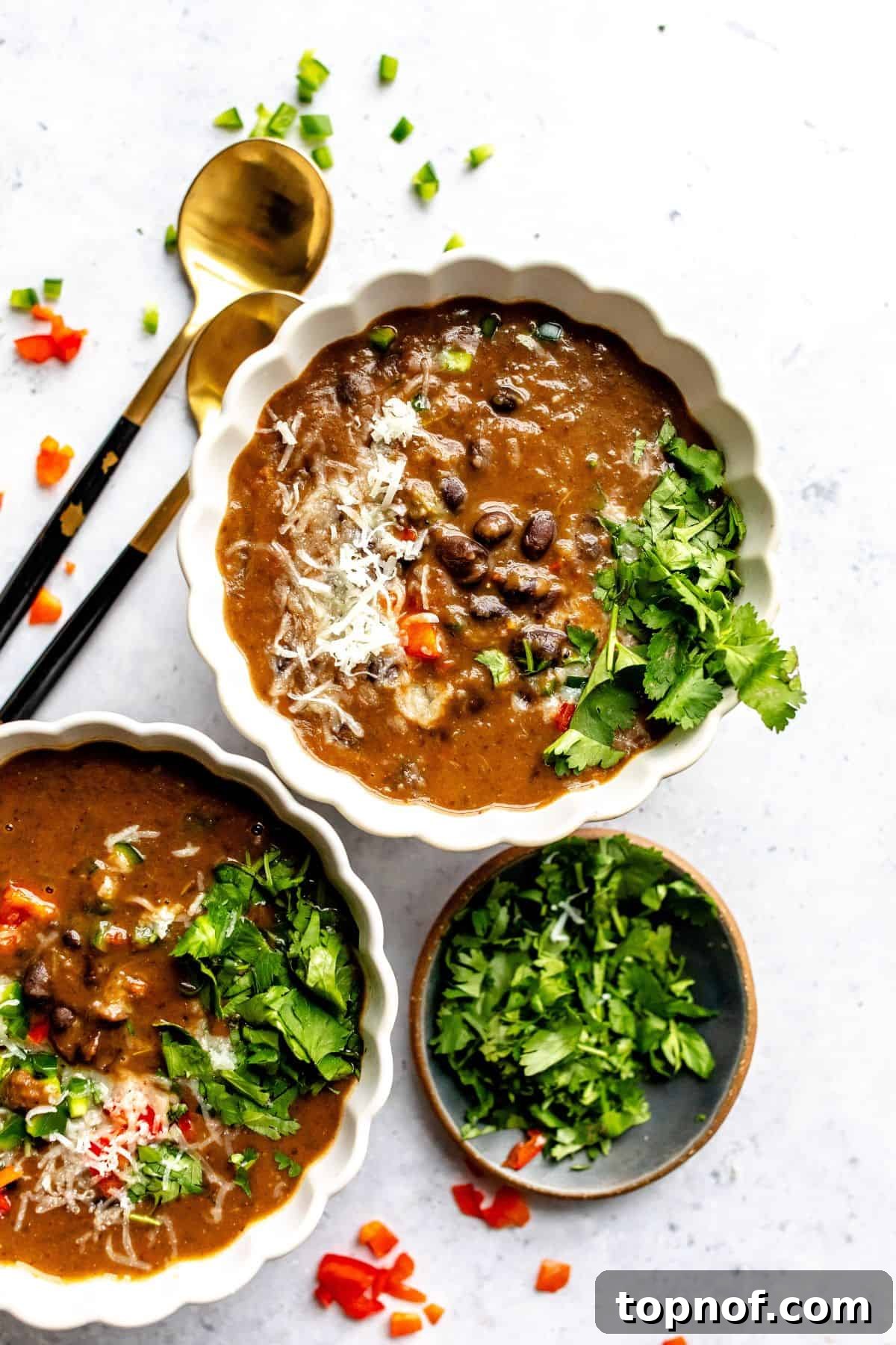 Rich Black Bean Comfort 2 A cozy white ceramic bowl filled with homemade Panera Black Bean Soup, garnished with fresh cilantro, with two spoons on the side. Perfect for a comforting meal.