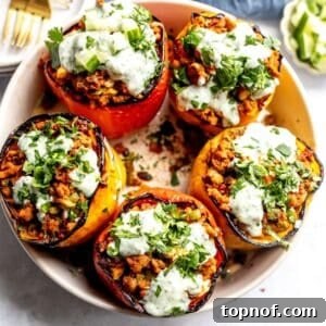 Ground turkey stuffed Peppers in a grey bowl with gold forks and plates on the side.