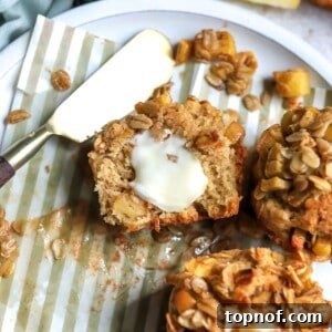 Apple spice muffins on a white ceramic plate with striped muffin liners and a pat of butter.