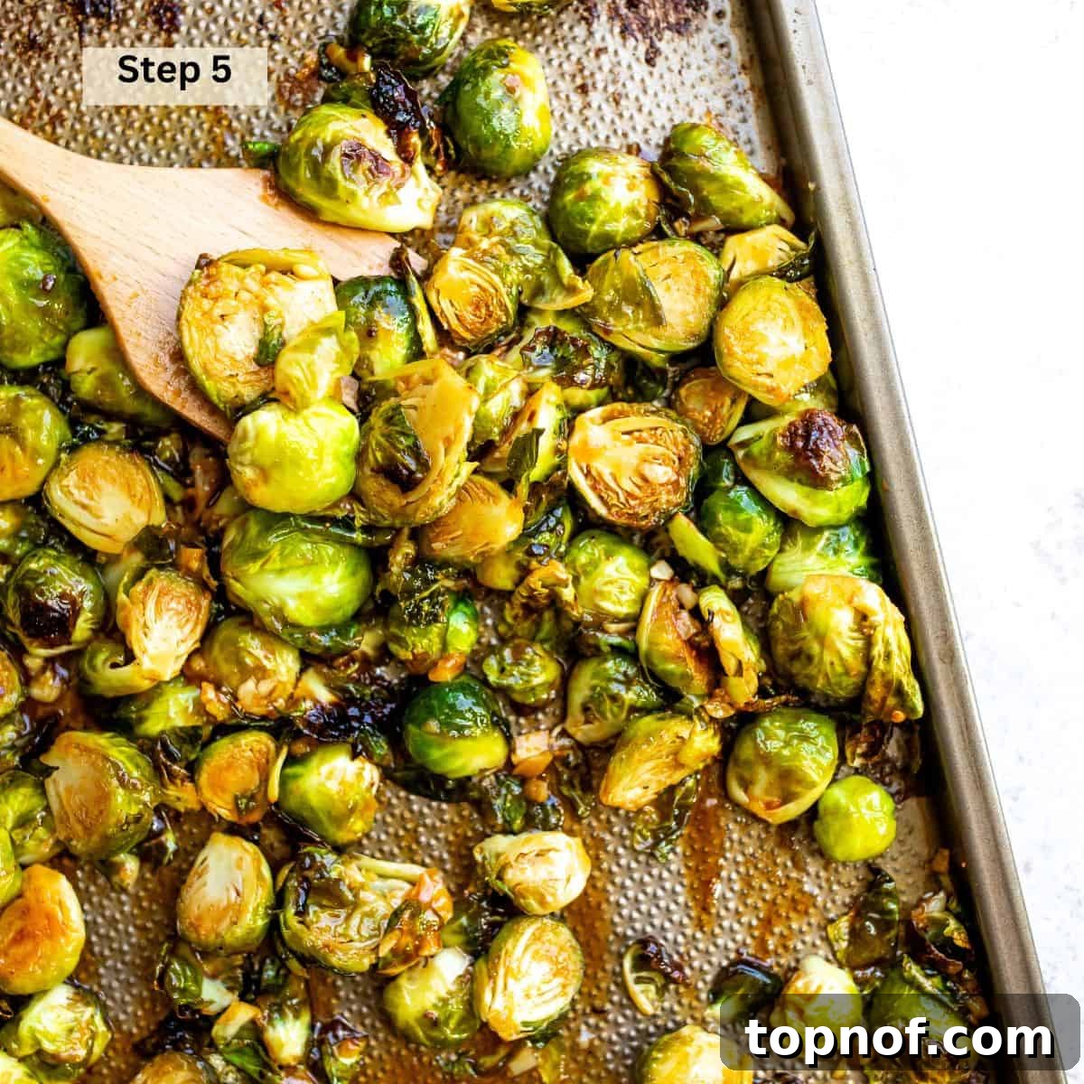 Brussel sprouts on a baking sheet with  sriracha and honey sauce. 