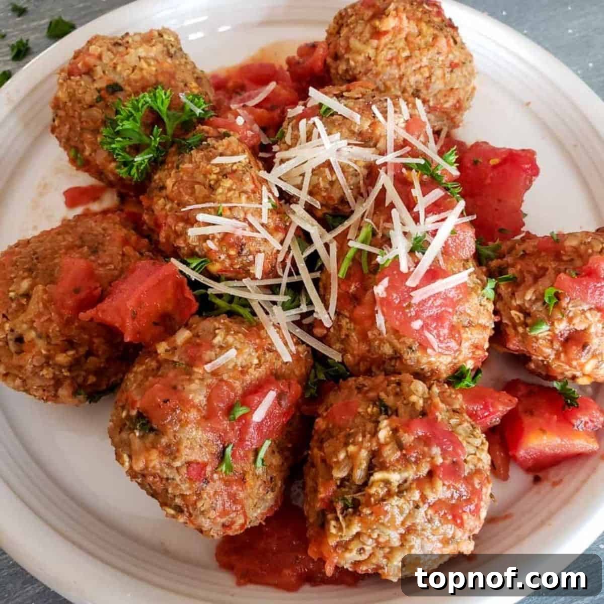 Wholesome Veggie Poppers 2 Close-up of golden brown vegetarian meatballs topped with melted cheese and fresh parsley, served on a white plate, ready to be enjoyed.