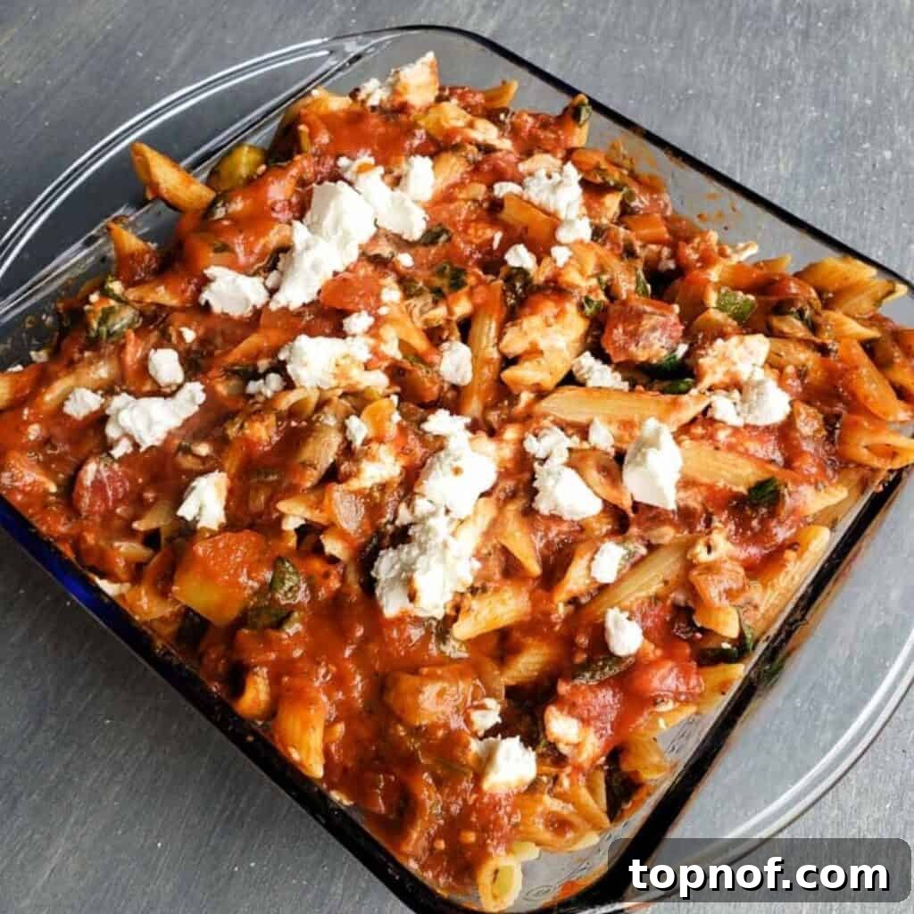 A close-up of the vegetarian pasta bake, showing the melted, golden-brown cheese and rich tomato sauce with visible vegetables.