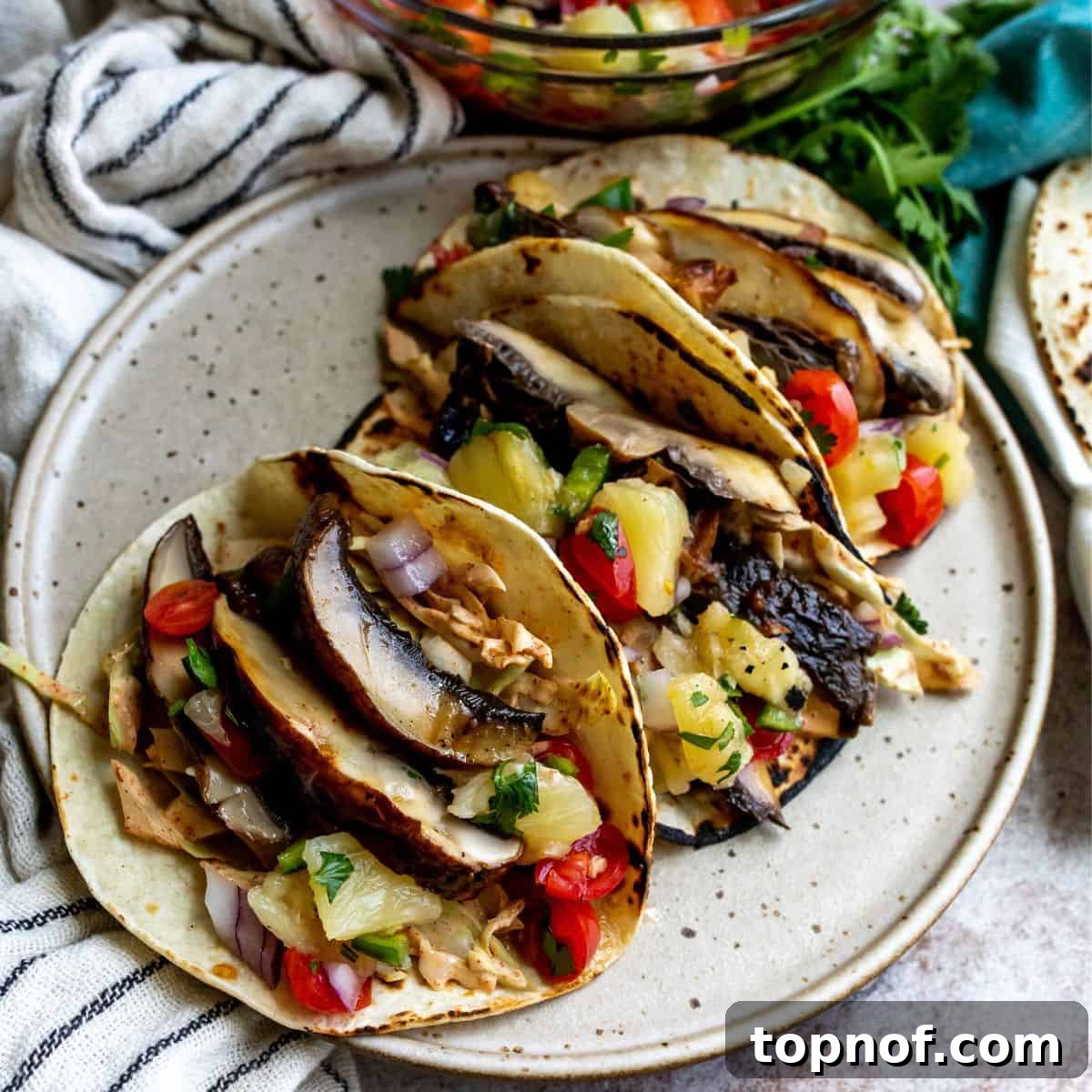 Umami Mushroom Asada Tacos 2 Flavorful Mushroom Asada Tacos topped with fresh salsa on a vibrant plate.