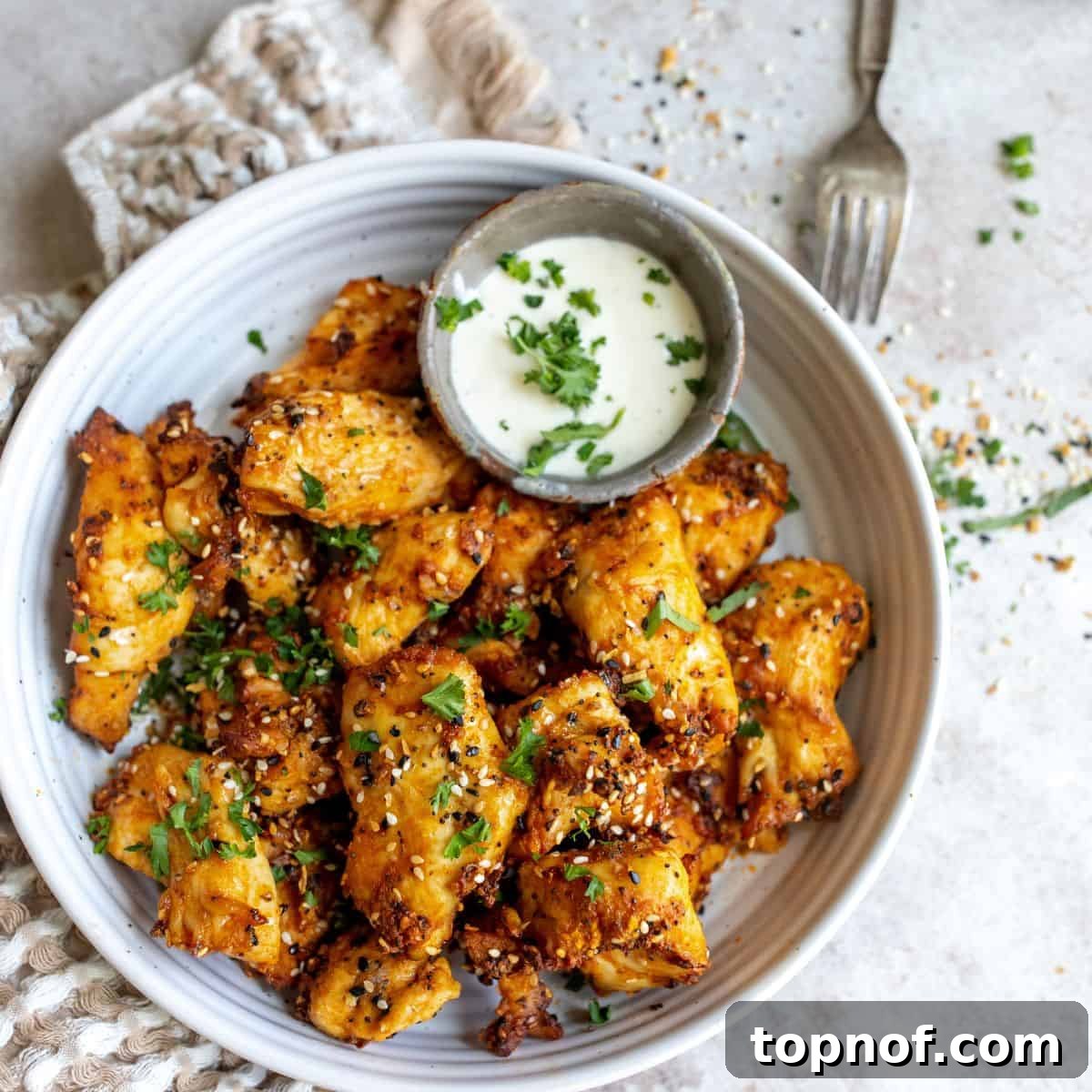 Pure Chicken Tenders 2 White bowl with Naked Chicken Tenders and seasoning, ready to be served with a side of dipping sauce.