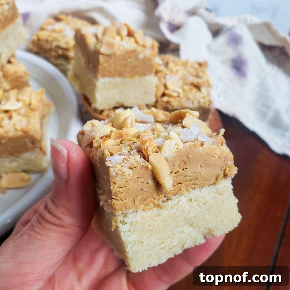 Heavenly Peanut Butter Squares 6 A hand holding a perfectly portioned vegan peanut butter bar, showcasing its layers.