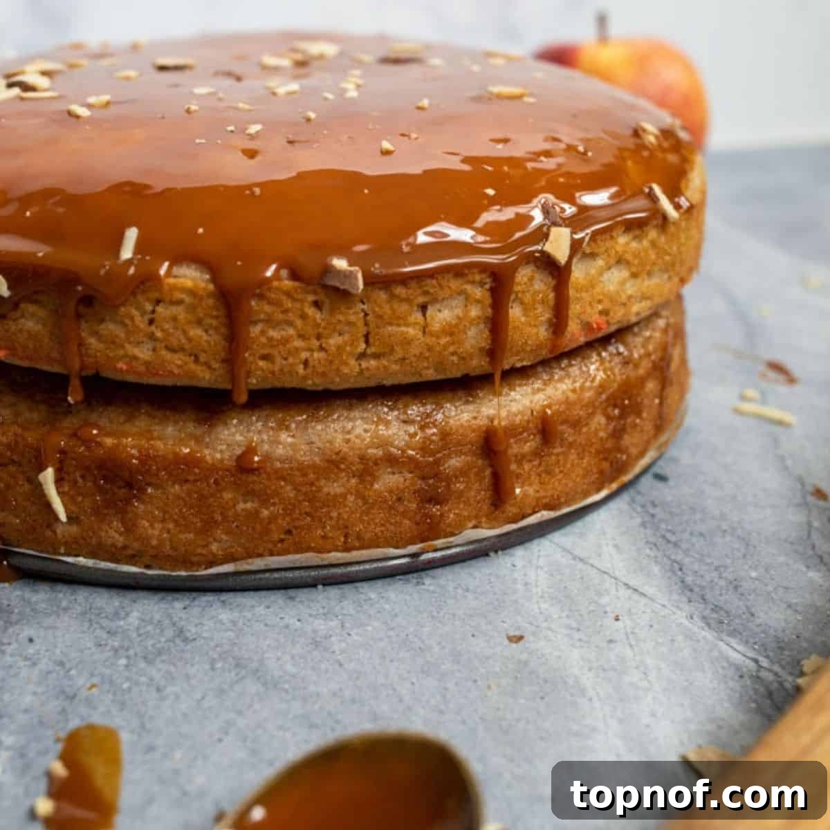 A slice of Caramel Apple Cake beautifully presented on a plate, topped with caramel and nuts.