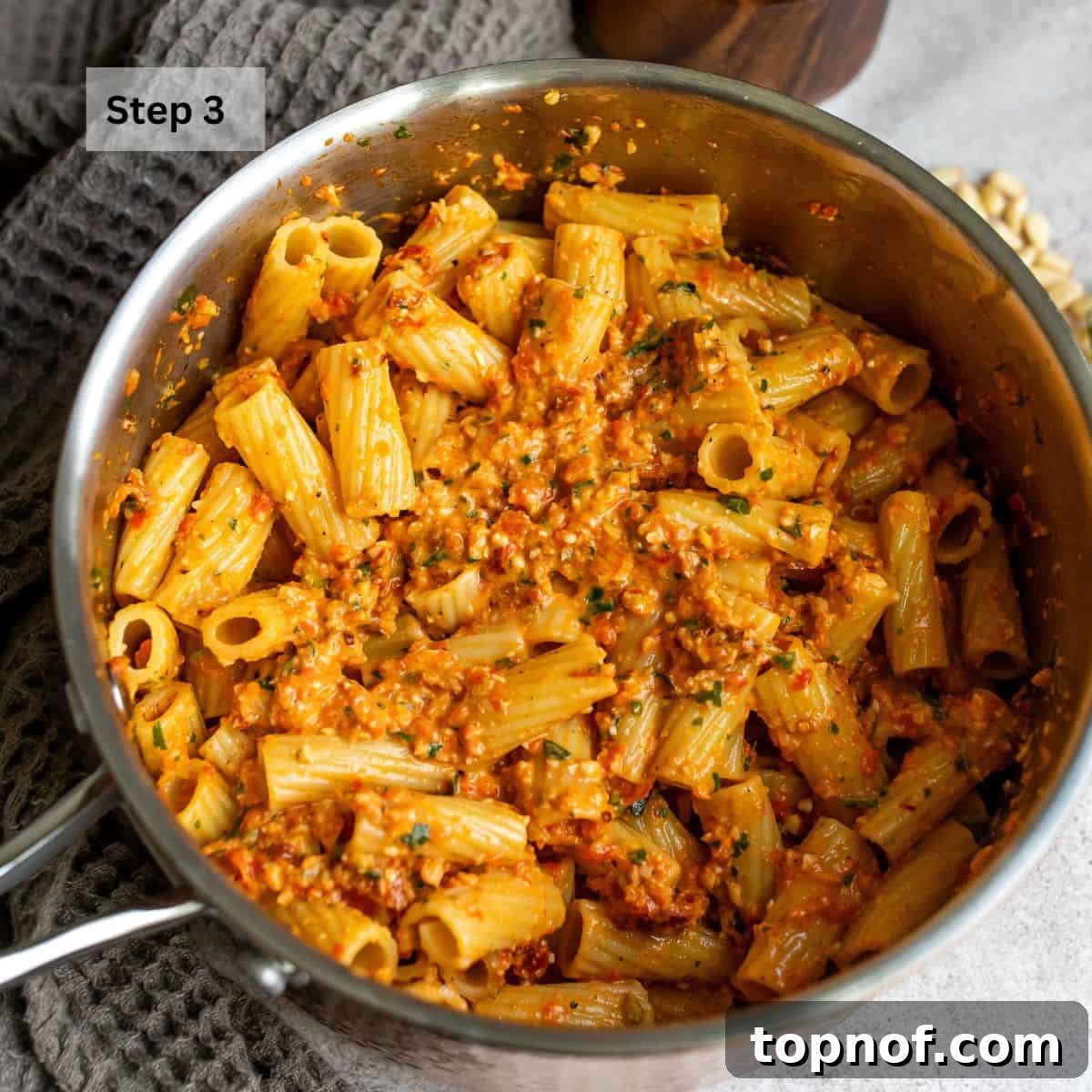 Roasted Red Pepper Pesto 5 A saucepan filled with perfectly cooked pasta tossed in vibrant red pepper pesto, ready to be served.