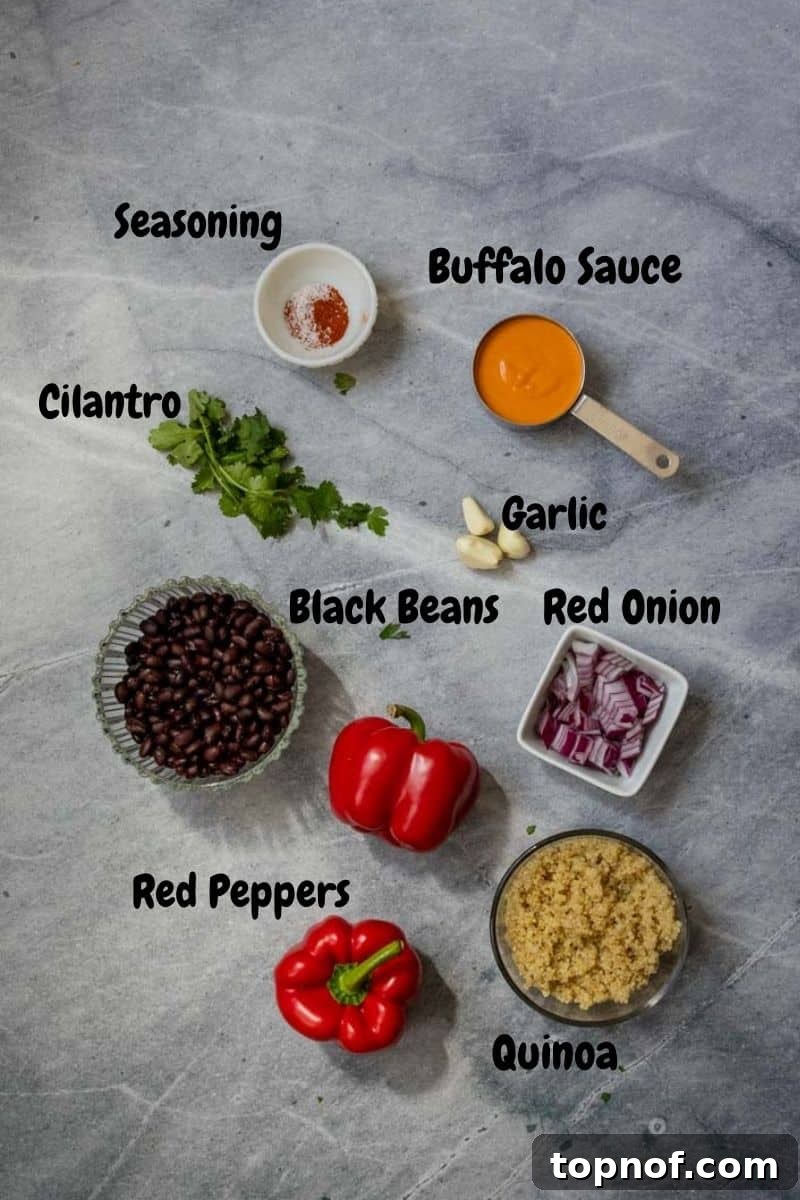 Plant-Powered Buffalo Stuffed Peppers 3 Fresh ingredients laid out on a kitchen surface: bell peppers, cooked quinoa, canned black beans, red onions, garlic, buffalo sauce, and cilantro, ready for vegetarian stuffed peppers.