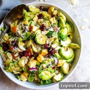 White ceramic bowl with brussel sprout salad in it and silver spoon.