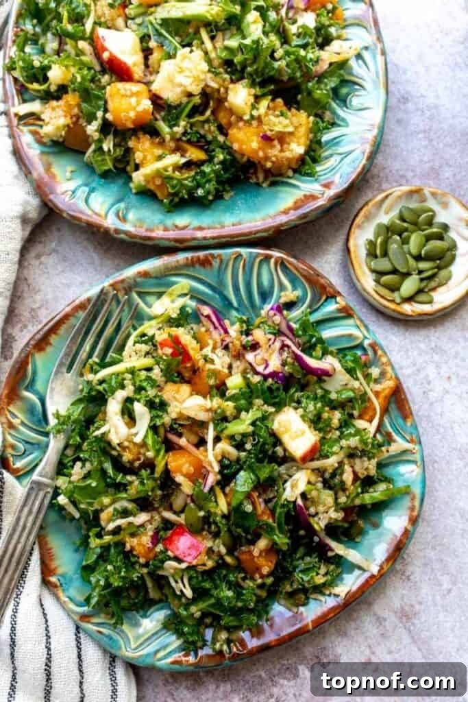 Kale Harvest Salad in a serving bowl, garnished with pumpkin seeds and cranberries.