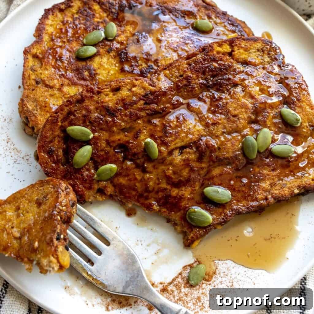 Ultimate Pumpkin Spice French Toast 5 A plate of Pumpkin Spice French Toast, beautifully garnished with syrup, with a fork holding a bite-sized piece.