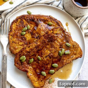 A slice of pumpkin french toast on a plate topped with pumpkin seeds and a light drizzle of syrup.