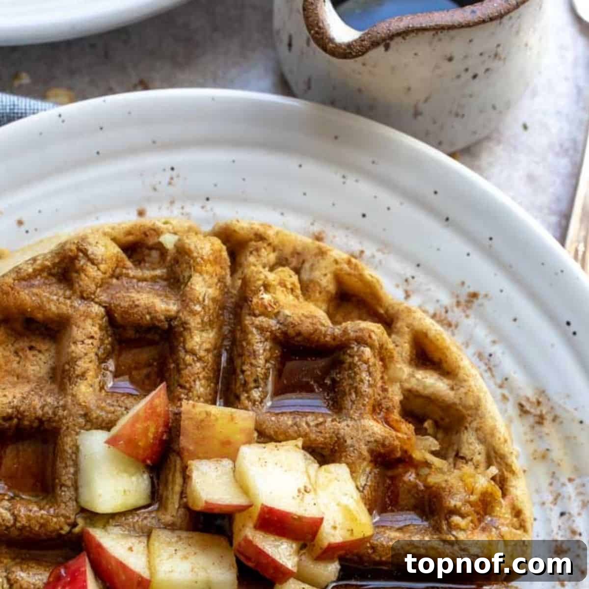Apple Pie Waffles 3 A close-up shot of golden brown apple waffles with a light dusting of powdered sugar, showcasing their crispy texture and delicious appeal.