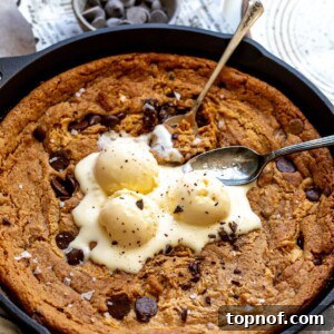 A perfectly baked, golden-brown Skillet Cookie in a cast iron pan, ready to be served.