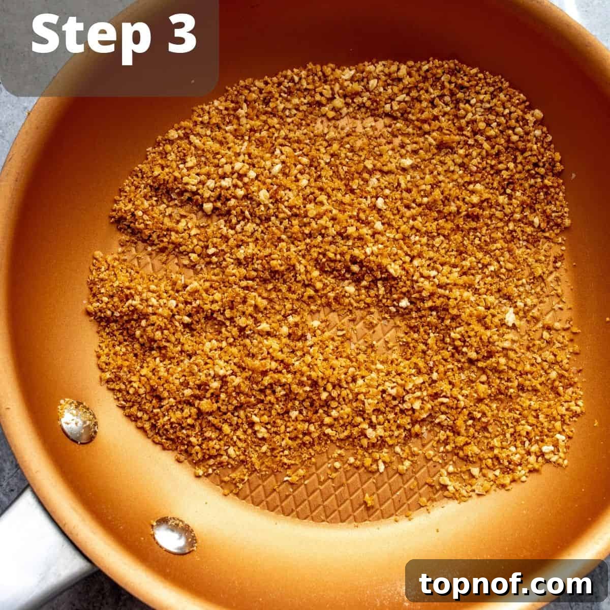 A spoonful of golden-brown toasted panko breadcrumbs, ready to be added as a crunchy topping to homemade ramen.