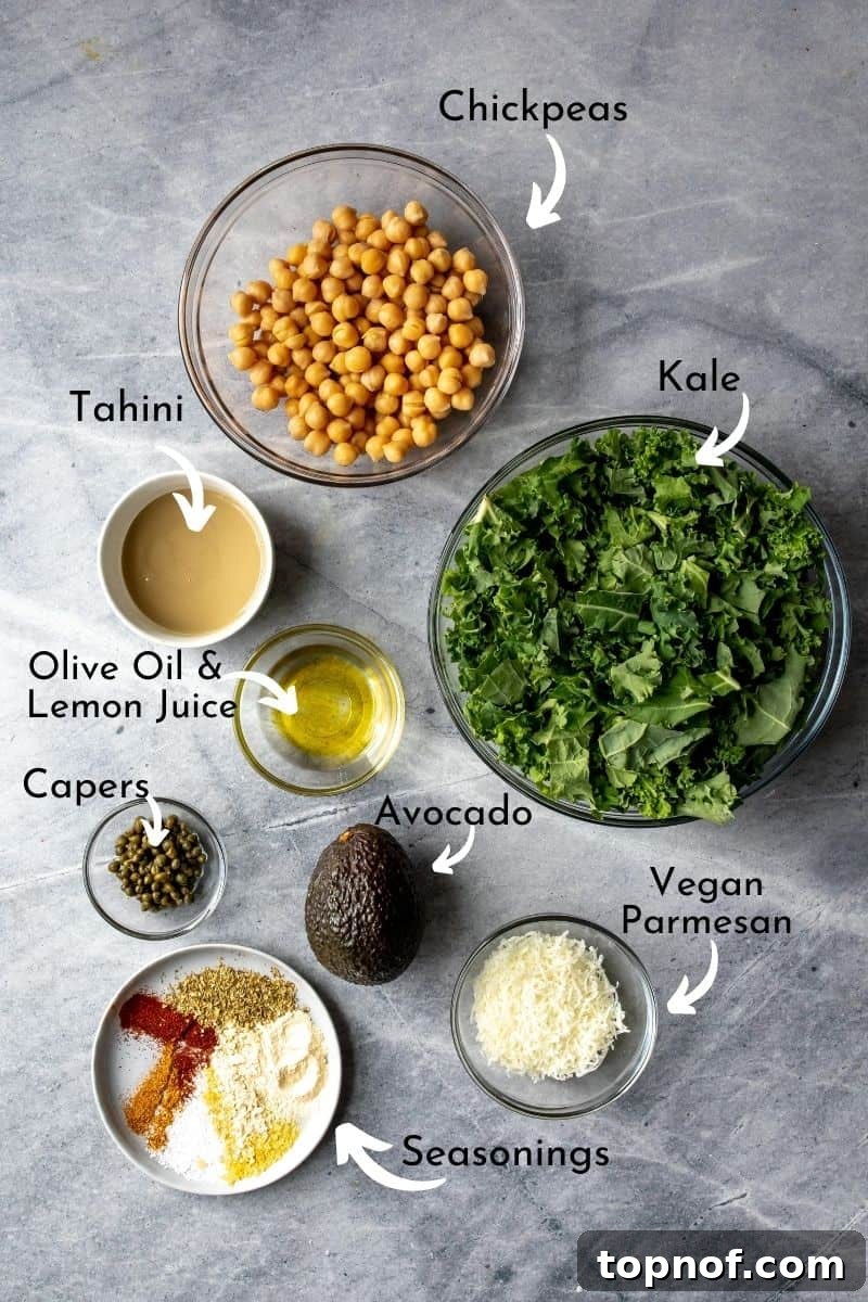 Zesty Lemon Kale Caesar 3 Ingredients laid out on a grey countertop, including kale, chickpeas, lemon, tahini, and spices, for a healthy kale and chickpea salad.