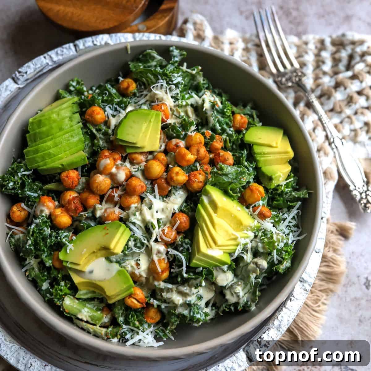 Zesty Lemon Kale Caesar 6 Kale and chickpea salad with all toppings in a grey bowl, accompanied by a fork.