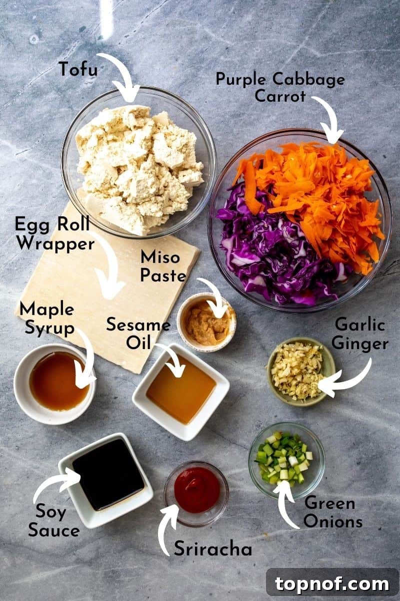 Various egg roll ingredients meticulously arranged in bowls on a grey board, showcasing fresh vegetables, tofu, and sauces.