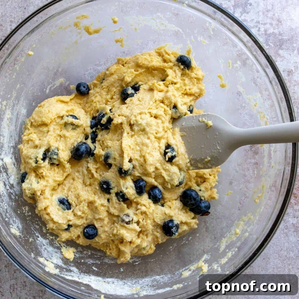 Fluffy Dairy-Free Cornbread with Optional Sweet Blueberries 4 Steps to make this recipe in a clear bowl with a spatula.