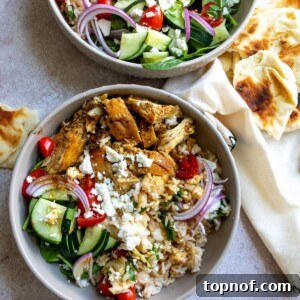 A vibrant and fully assembled Mediterranean Chicken Bowl with rice, chicken, fresh vegetables, and feta cheese.