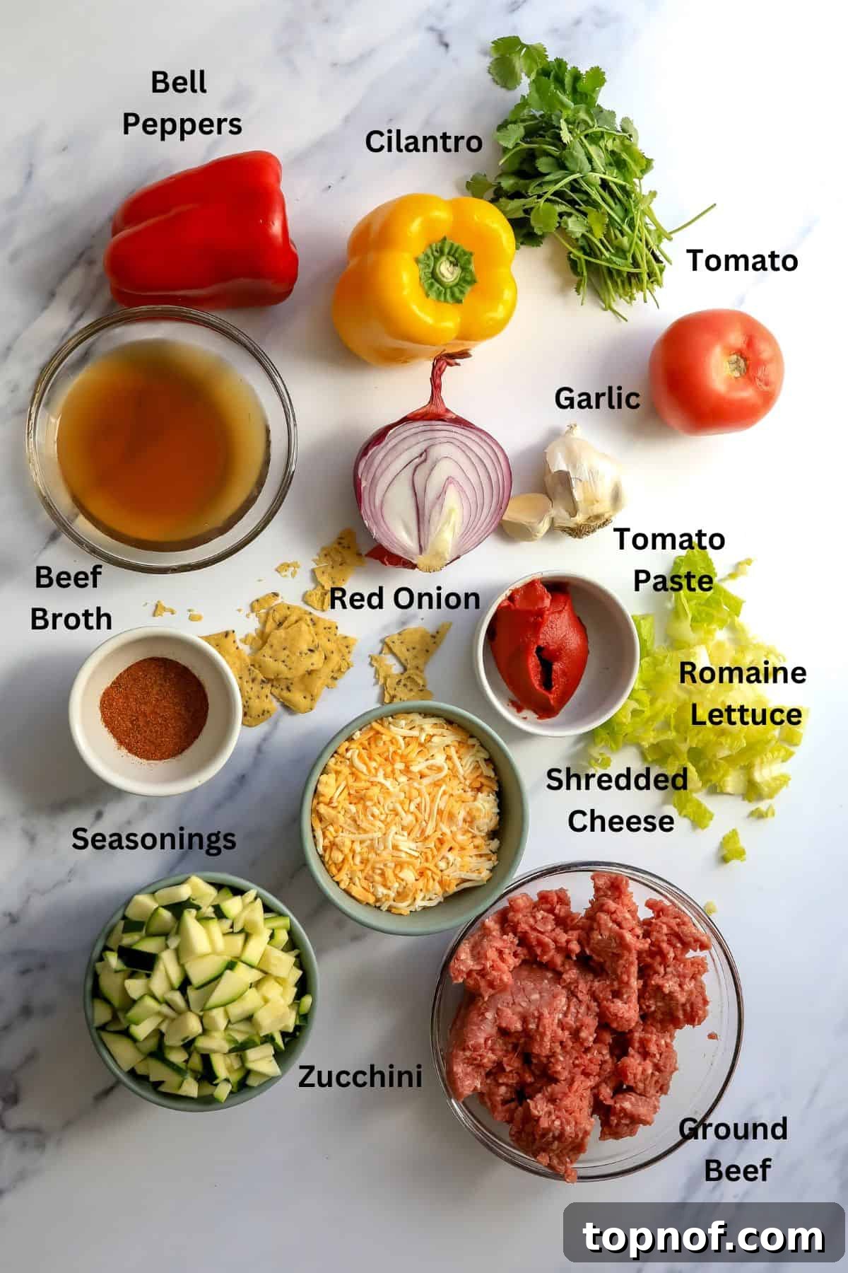 Fiesta Taco Stuffed Peppers 3 Various ingredients laid out on a kitchen counter in small bowls and plates, including bell peppers, ground meat, zucchini, onion, garlic, spices, and cilantro.