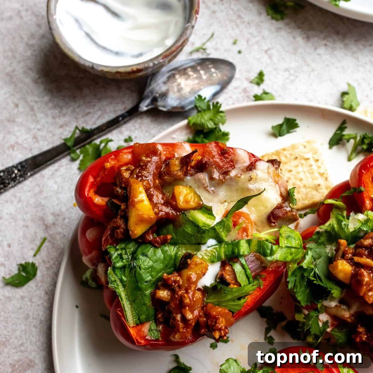 Fiesta Taco Stuffed Peppers 5 Close-up photo of baked Mexican stuffed peppers topped with melted cheese and fresh cilantro, glistening and ready to eat.