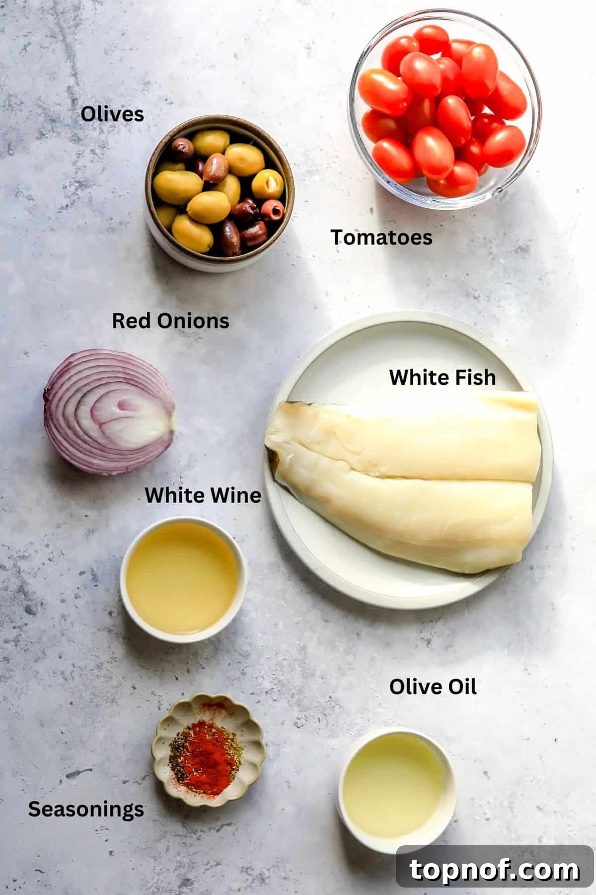 Herbed Mediterranean Fish Bake 3 Assortment of fresh ingredients laid out for Mediterranean baked fish, including white fish, olives, tomatoes, and herbs.