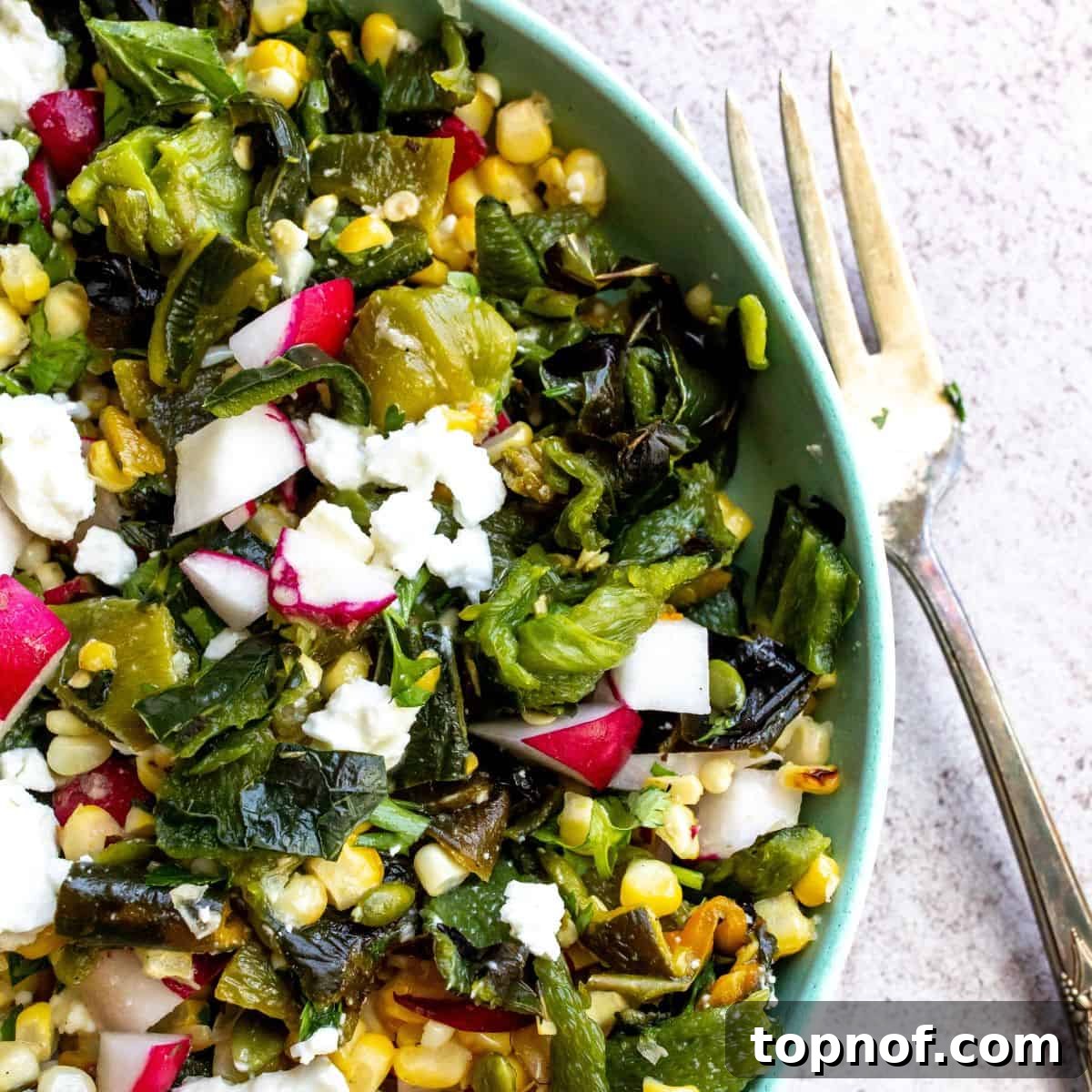 Charred Corn and Poblano Salad 2 Close-up of a vibrant Roasted Corn Salad with Poblano Peppers in a blue bowl, showcasing roasted kernels and chopped ingredients.