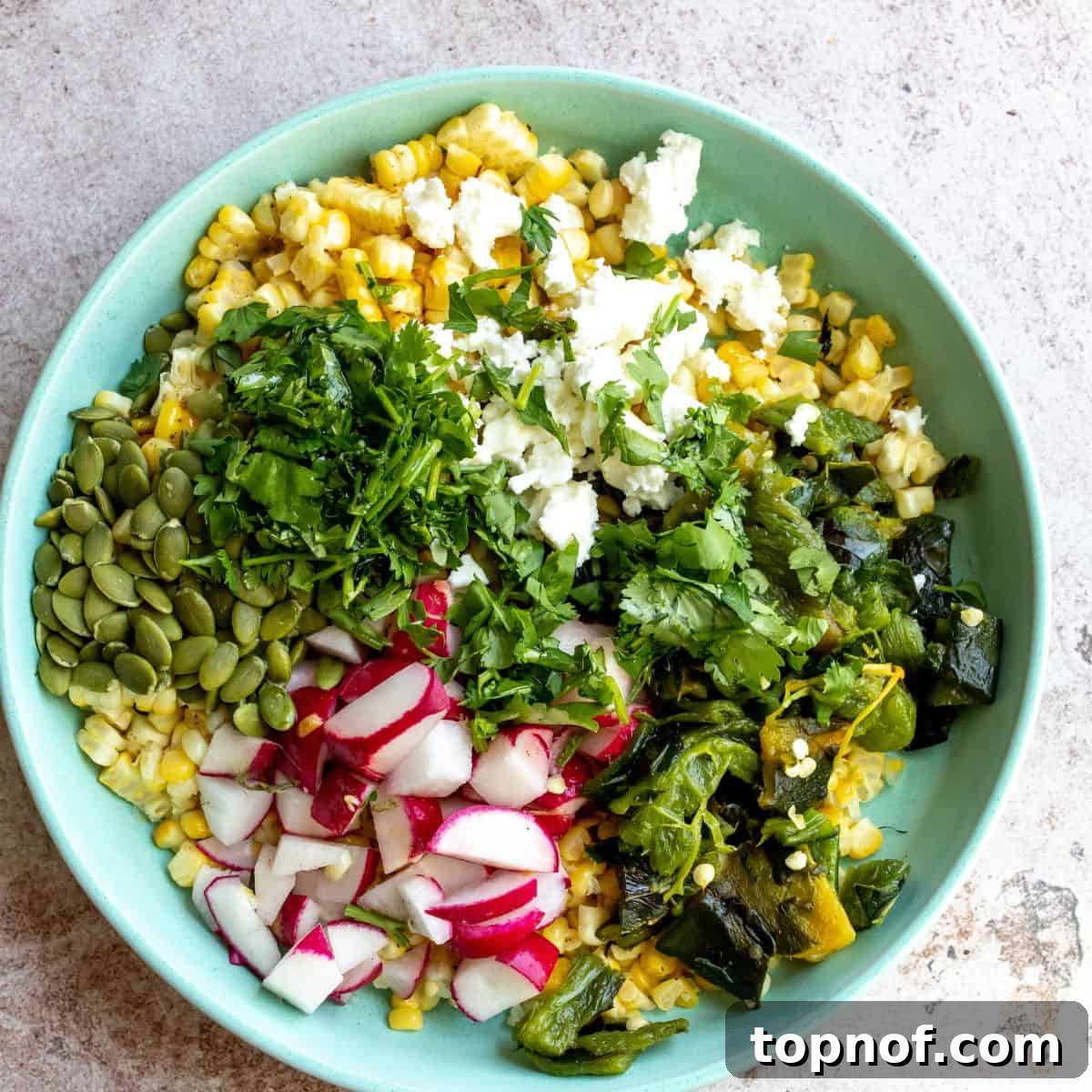 Charred Corn and Poblano Salad 5 Roasted Corn Salad with Poblano Peppers being mixed in a large green bowl, ready to be served.