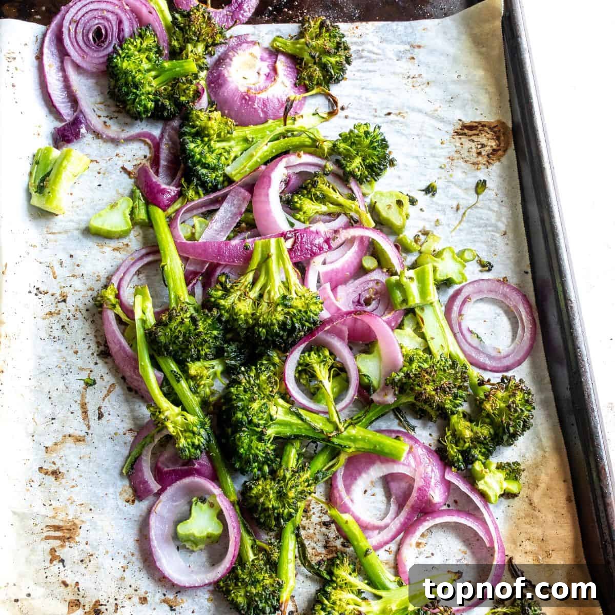 Vibrant Quinoa & Roasted Broccoli Power Bowls 4 Freshly chopped broccoli and red onion seasoned with herbs and olive oil, spread on parchment paper on a baking sheet, ready for roasting.