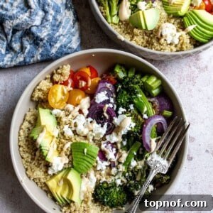 A vibrant Quinoa Veggie Bowl in a grey bowl, garnished with fresh herbs, alongside a silver fork.