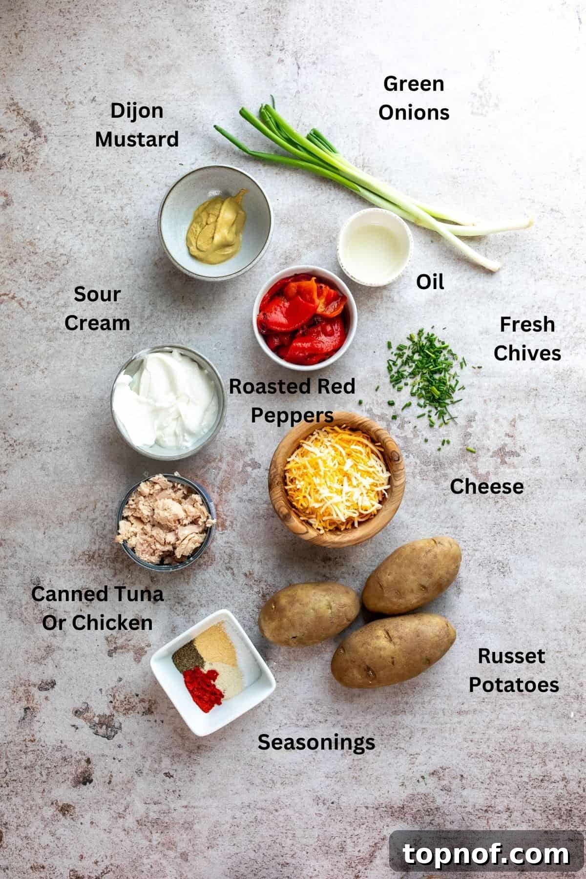 Ingredients needed to make tuna potatoes in small white bowls, including russet potatoes, roasted red peppers, tuna, and seasonings.