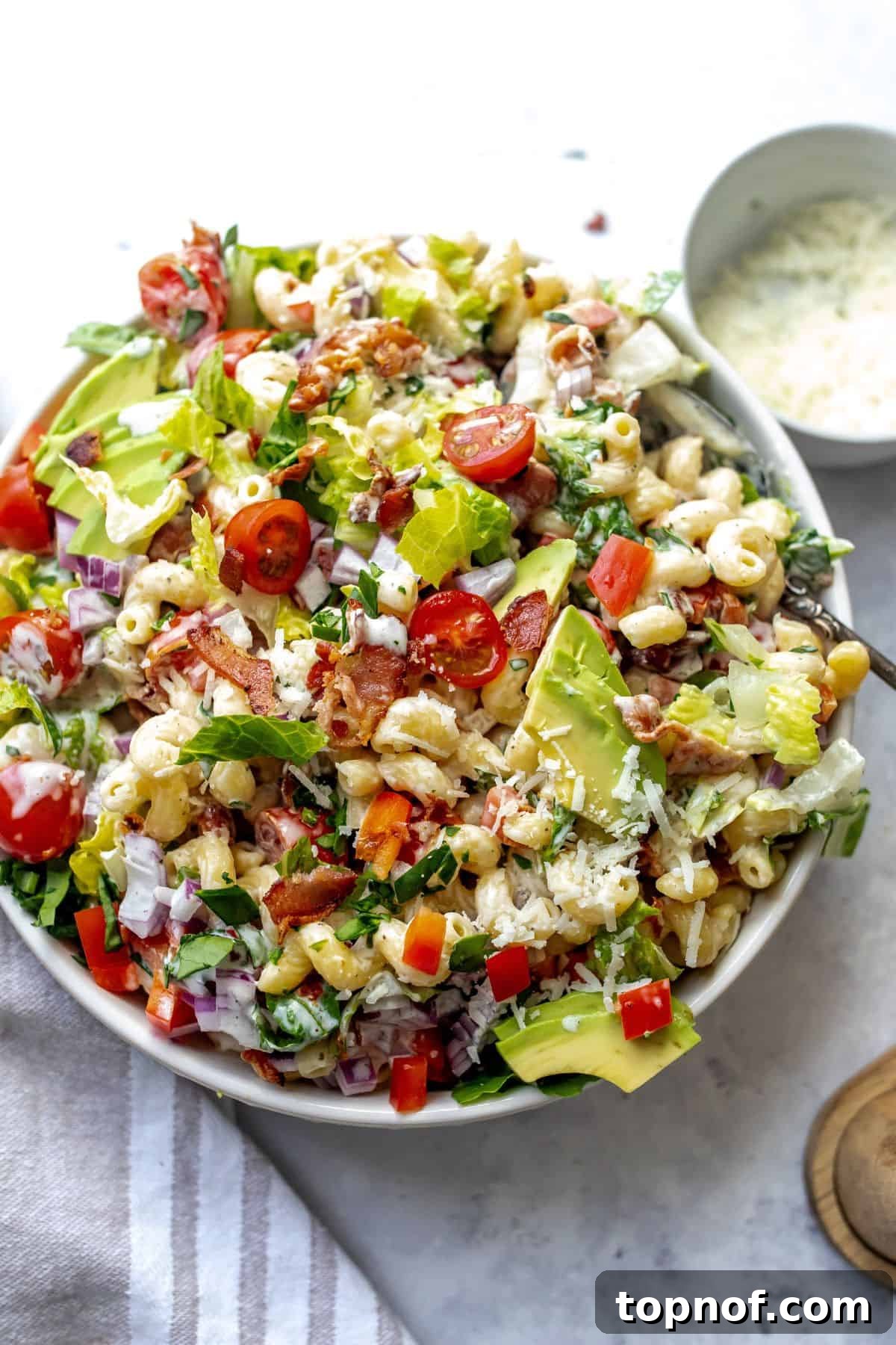 Savory BLT Pasta Toss 2 BLT pasta salad on a green plate with a fork, showcasing vibrant colors and textures.