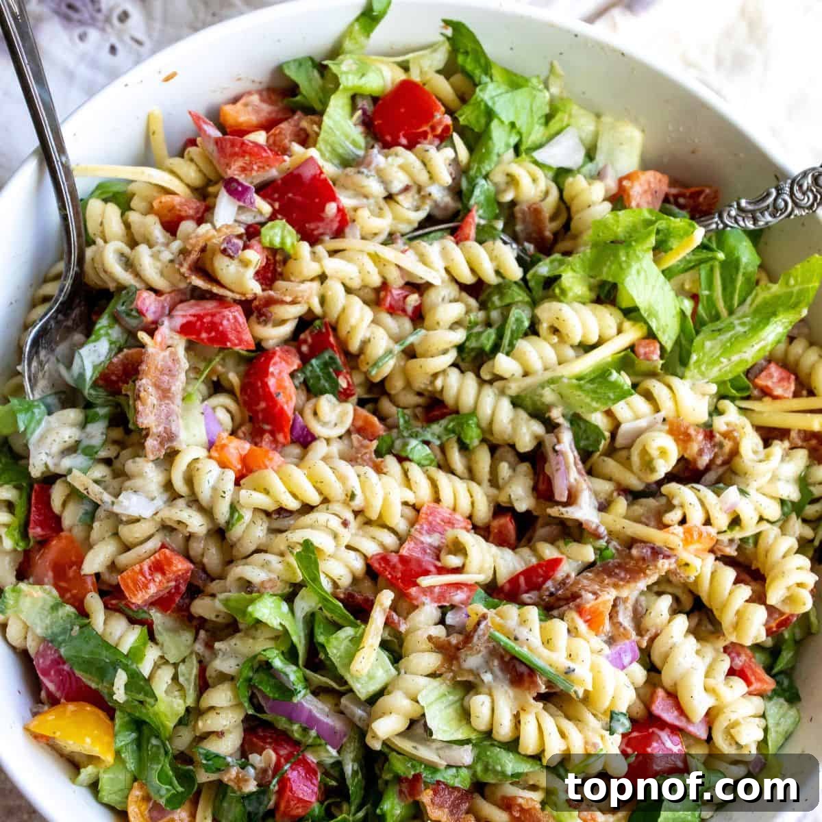 Savory BLT Pasta Toss 6 A large bowl of BLT pasta salad with a serving spoon, ready to be enjoyed.