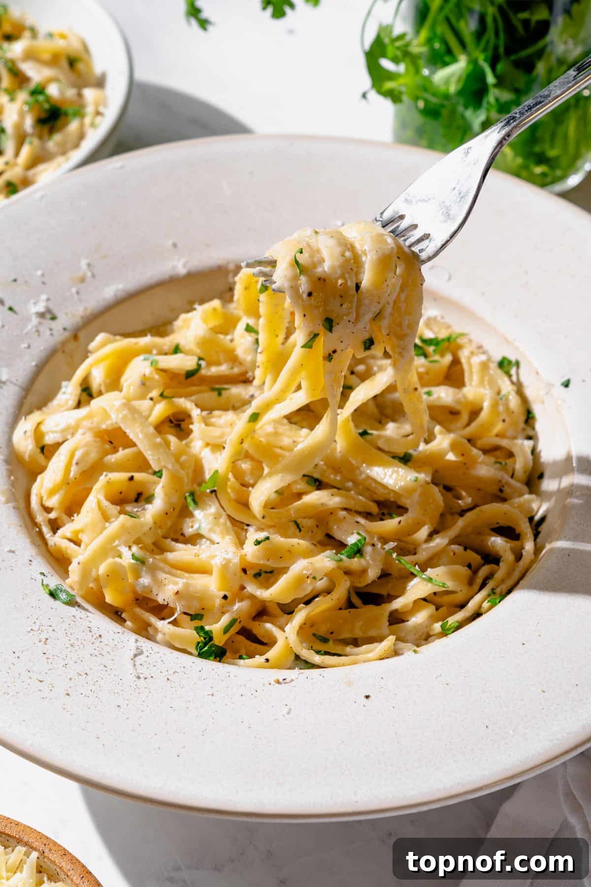 High Protein Cottage Cheese Alfredo Sauce in a white bowl with pasta on a fork.