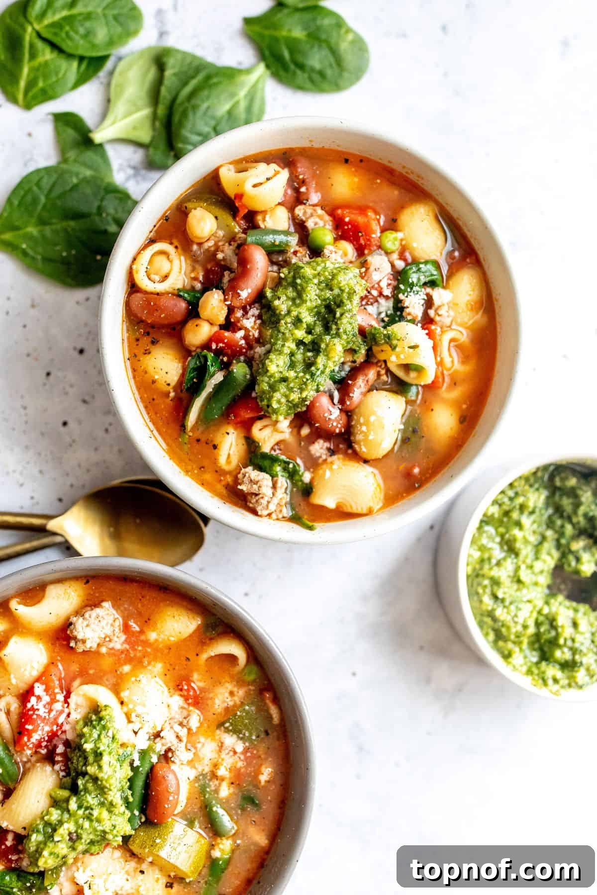 Hearty Turkey Minestrone 2 Delicious Minestrone Soup with lean ground turkey, pasta, and vibrant vegetables, served in white ceramic bowls, garnished with fresh pesto.