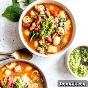Delicious Minestrone Soup with Ground Turkey, garnished with pesto and Parmesan cheese.