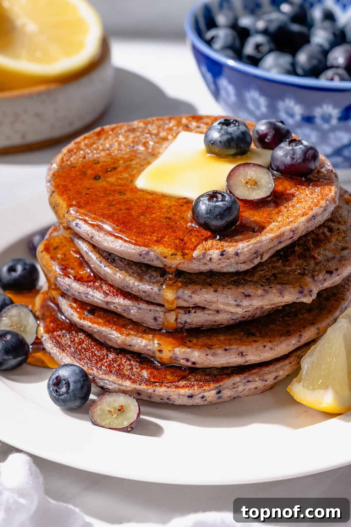 Zesty Lemon Blueberry Protein Pancakes 2 Fluffy lemon blueberry cottage cheese pancakes served with maple syrup for breakfast, garnished with fresh blueberries.